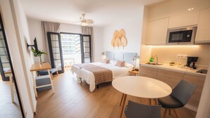 Una habitación de hotel moderna con cama, mesita de noche y una pequeña zona de comedor con mesa y sillas.
