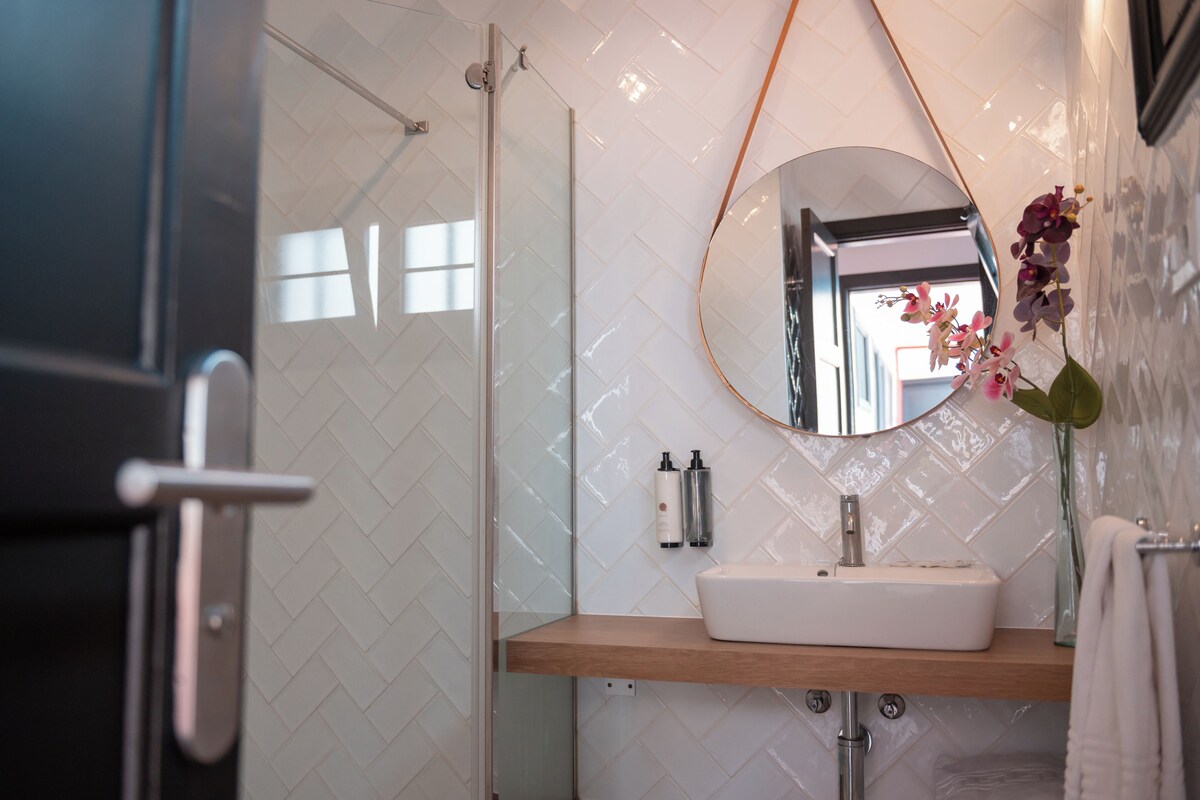 A bathroom with a white sink, a mirror, and a shower.