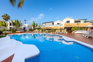 Una piscina al aire libre, sillones reclinables de piscina
