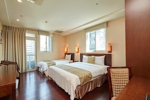 Comfortable family room with a large bed and two smaller beds, a desk, and large windows.