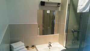 A bathroom with a glass-enclosed shower, a white sink, and a mirror above the sink. - Nyton Hotel (Ely)
