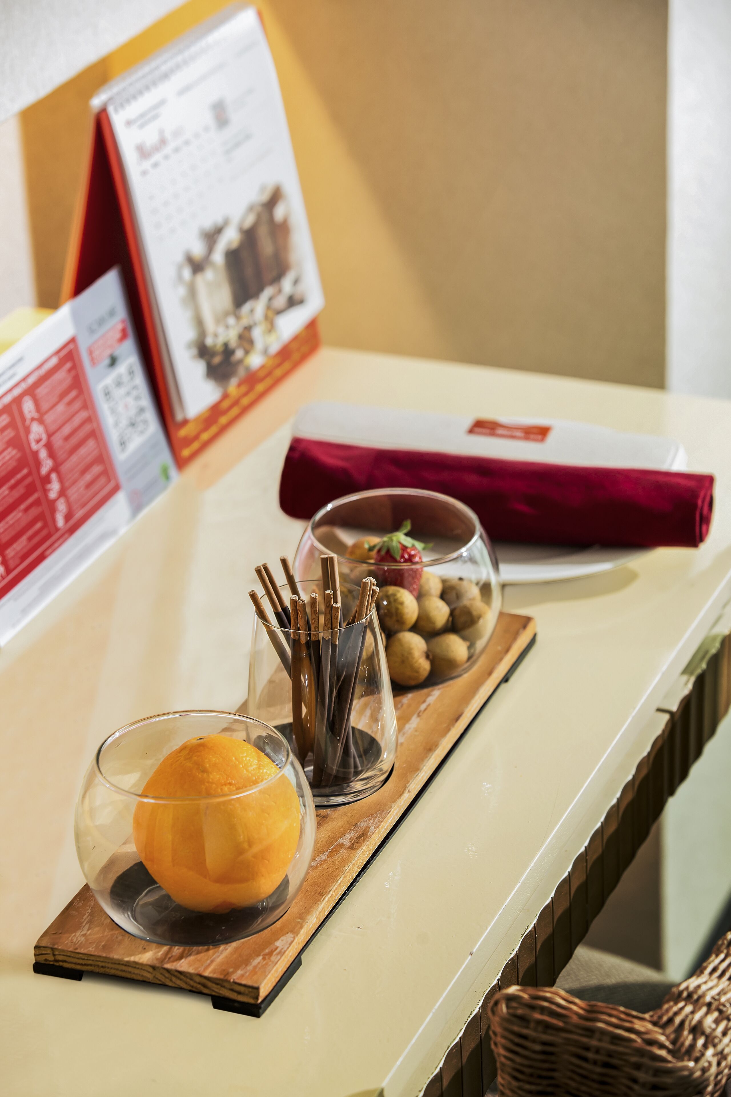 A reception area with a counter displaying a glass bowl of snacks, a glass of orange juice, and a red napkin.