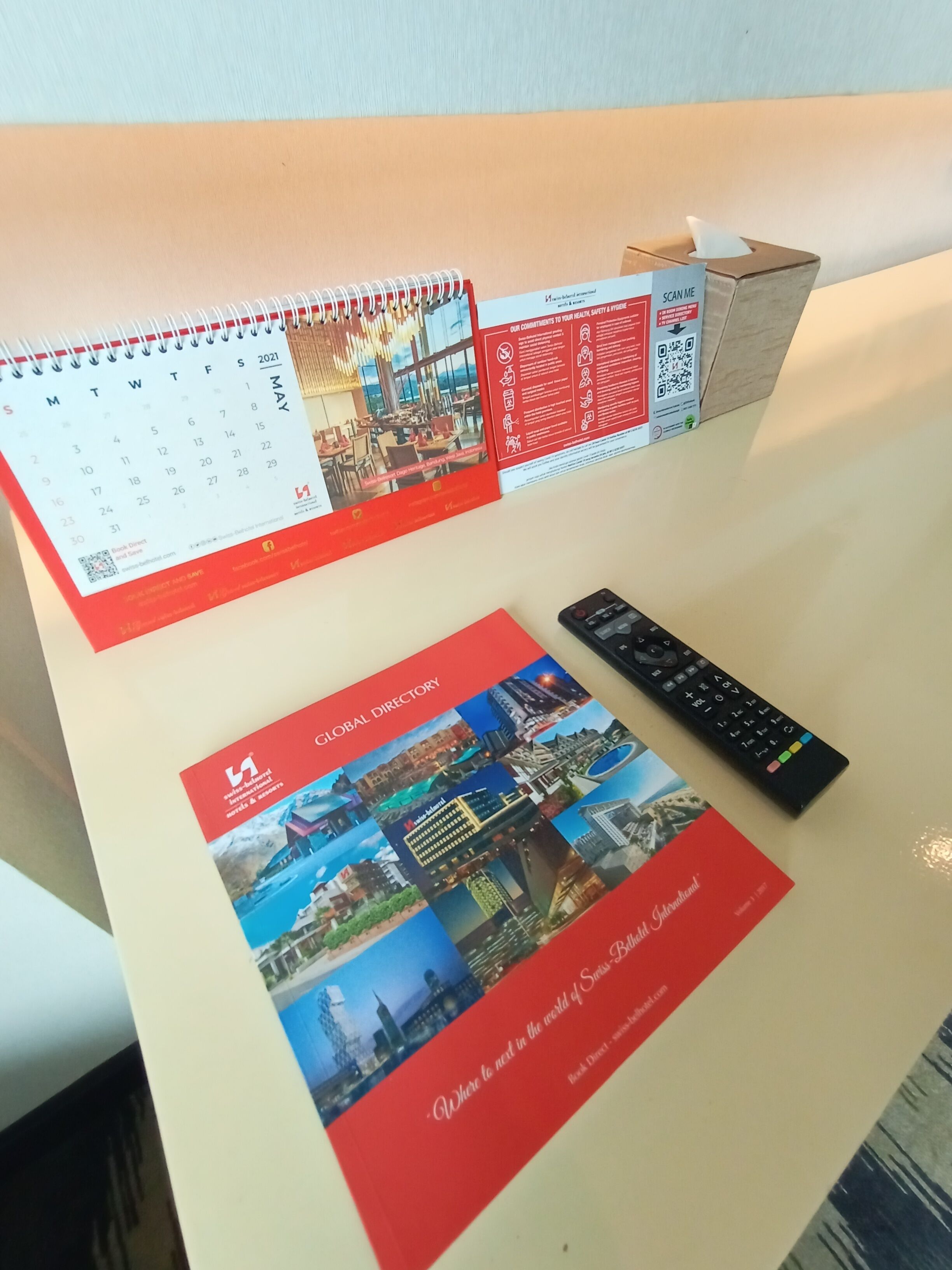 Un bureau avec un calendrier, une brochure et une télécommande.
