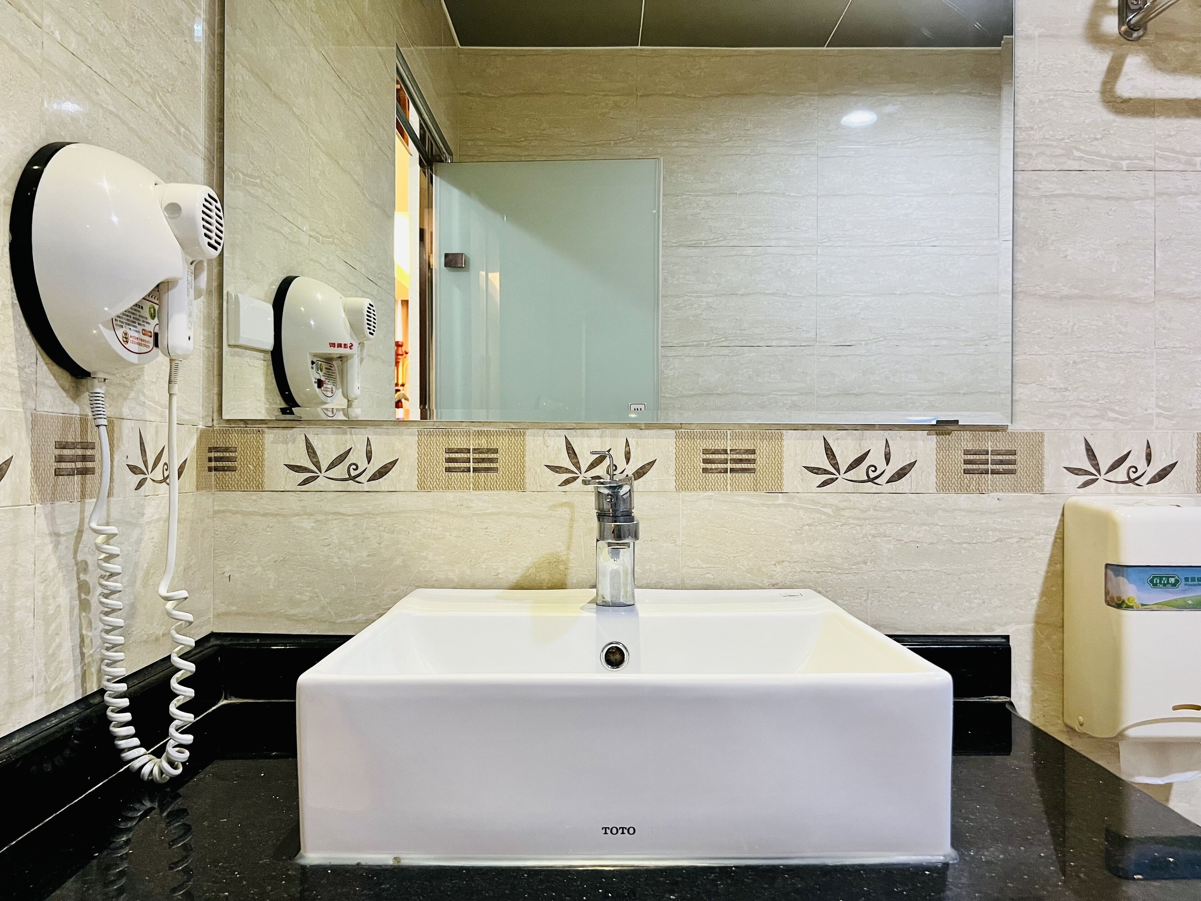 Un baño con un lavabo blanco, un secador de pelo y un espejo.