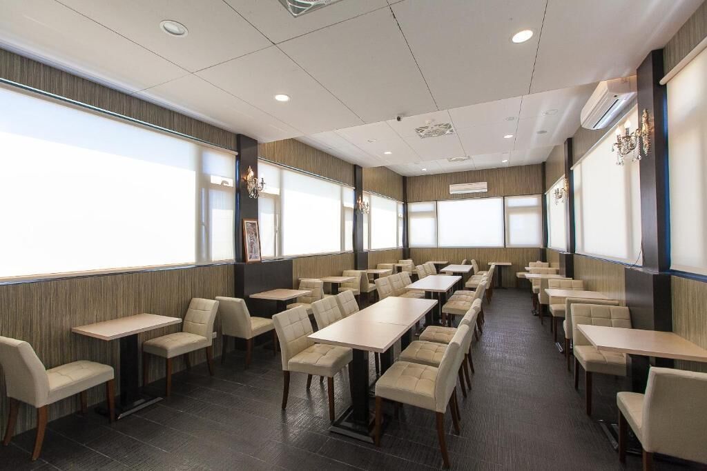 A conference room with multiple tables and chairs, large windows, and a modern ceiling design.