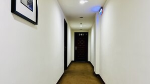 A narrow, carpeted hallway with white walls, a framed picture on the left, and a door marked '501' at the end. - Mucha Hotel (Yilan)