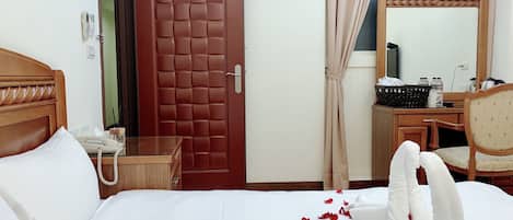 A hotel room with a bed, a desk, a telephone, a mirror, and a door marked with the number 302.