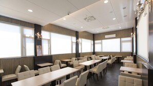 A dining area with multiple tables and booths, large windows, and a chandelier. - Mucha Hotel (Yilan)