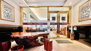 A lobby with a wooden reception desk, seating area, and glass doors leading to a lounge. - Mucha Hotel (Yilan)