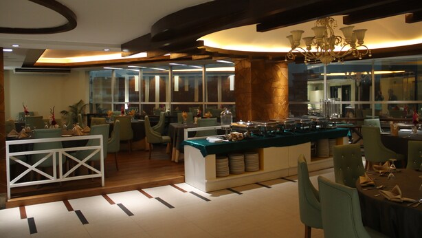 A modern dining area with a buffet setup, glass partitions, and contemporary furniture. - Hotel Valley Garden (Sylhet)