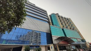 A hotel with a modern glass facade, a curved blue glass tower, and a sign for Hotel Valley Gardens. - Hotel Valley Garden (Sylhet)