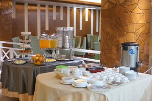 A breakfast buffet setup with various food items, a coffee machine, and a fruit bowl. - Hotel Valley Garden (Sylhet)
