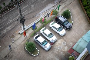 A parking lot with several cars and a pedestrian walking by. - Hotel Valley Garden (Sylhet)