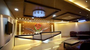 A modern lobby with a central staircase, a decorative wall, and leather seating areas. - Hotel Valley Garden (Sylhet)