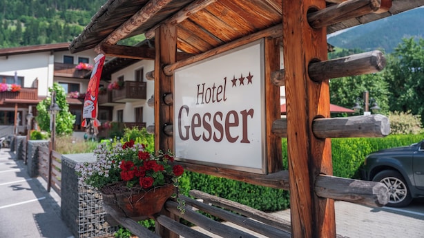 Une enseigne en bois indiquant l’hôtel Gesser, avec une vue sur les environs.