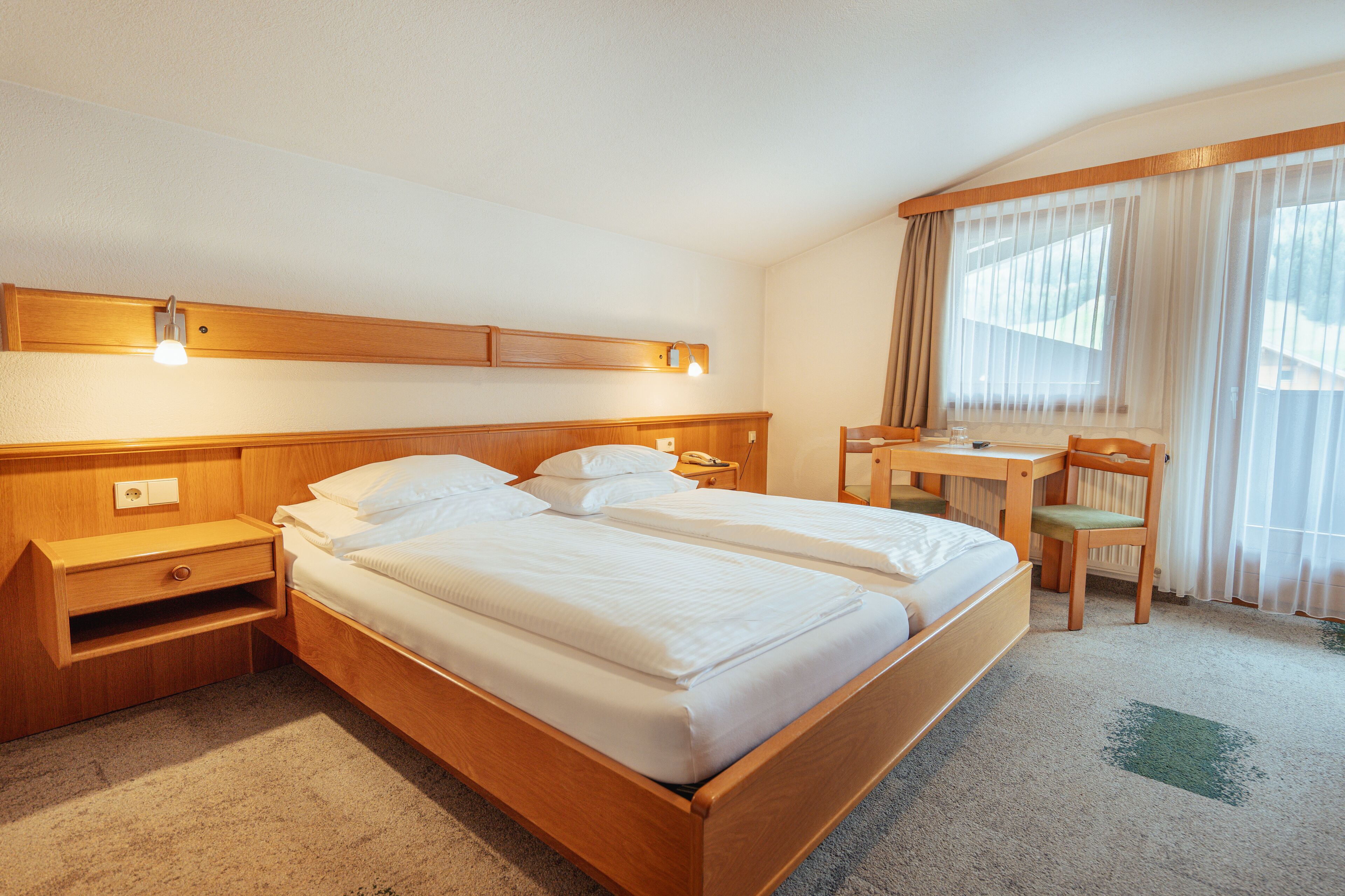 A hotel room with a wooden bed, a desk, and a chair.