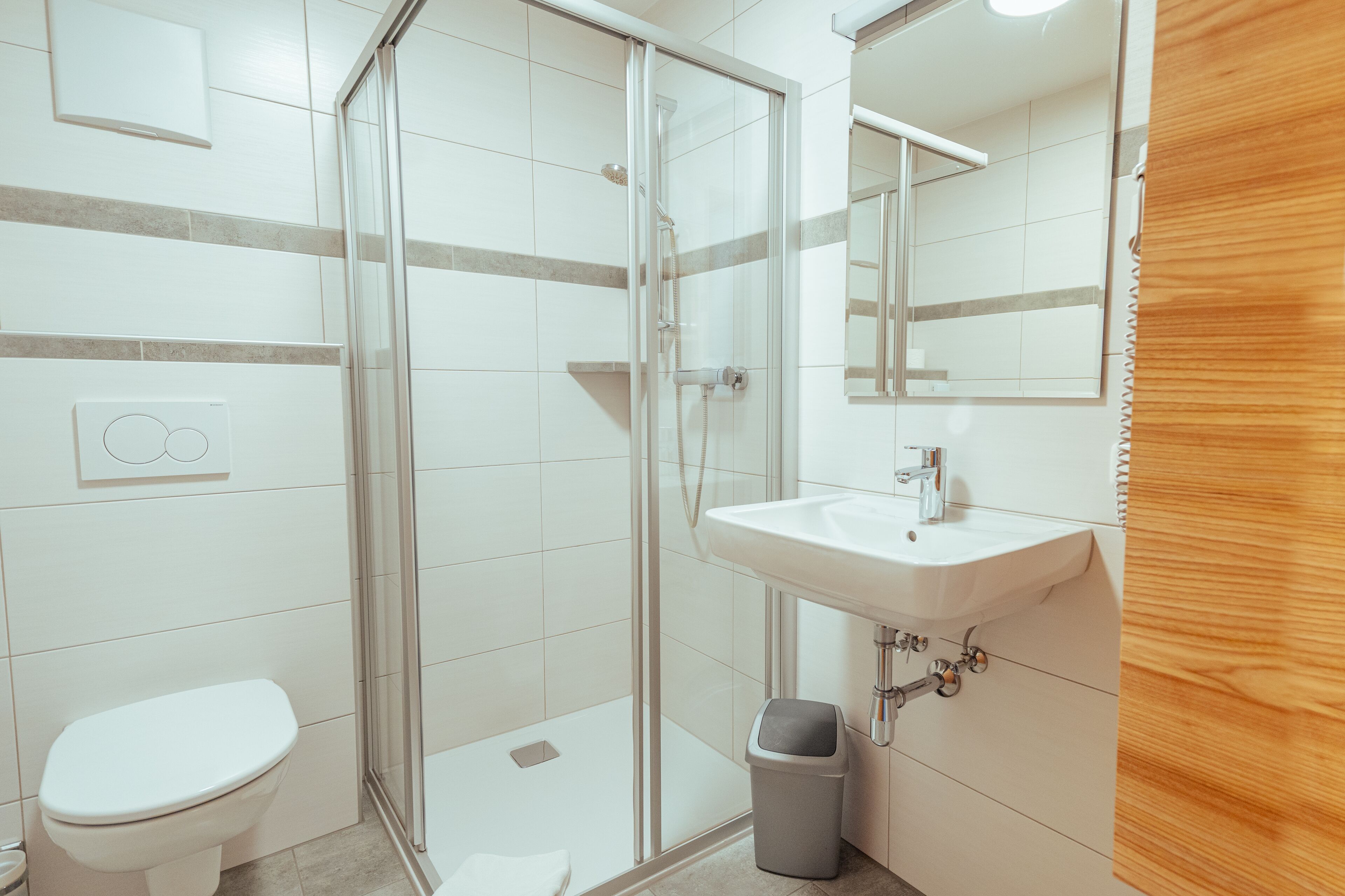Une salle de bain moderne avec une douche à parois de verre, un lavabo blanc et des toilettes.