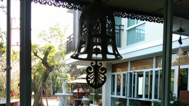 A view of a courtyard with a fountain, surrounded by potted plants and a hanging lantern. - Herry Residence (Chiang Mai)