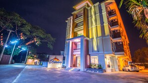 A modern hotel with a prominent entrance, multiple balconies, and a well-lit facade. - Herry Residence (Chiang Mai)