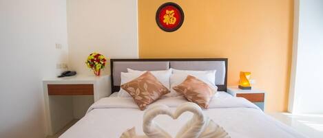 Una habitación de hotel con cama, mesita de noche, decoración en la pared y un jarrón de flores.