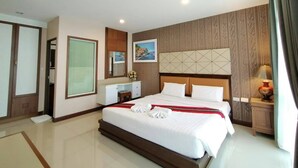 A hotel room with a large bed, a desk, a mirror, and a painting on the wall. - Herry Residence (Chiang Mai)