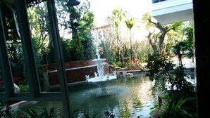 A serene indoor garden with a central water feature, surrounded by lush greenery and various plants. - Herry Residence (Chiang Mai)