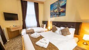 Une chambre d’hôtel avec deux lits, un téléviseur à écran plat, un tableau représentant un pont et un sol recouvert de moquette.