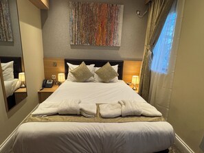 A hotel room with a large bed, two bedside lamps, a telephone, and a mirror on one side. - Shoreditch Inn (London)