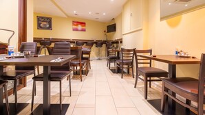 Un restaurant avec plusieurs tables et chaises, un téléviseur fixé au mur et un ventilateur de plafond.