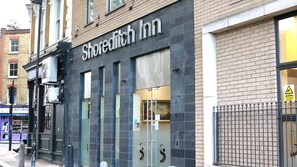 A hotel named 'Shoreditch Inn' with a modern facade, large windows, and a visible security warning sign. - Shoreditch Inn (London)