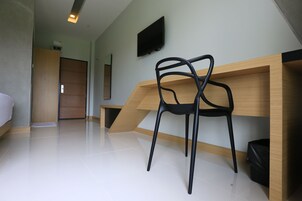Una habitación moderna con un escritorio de madera, una silla negra, un televisor de pantalla plana y una cama.