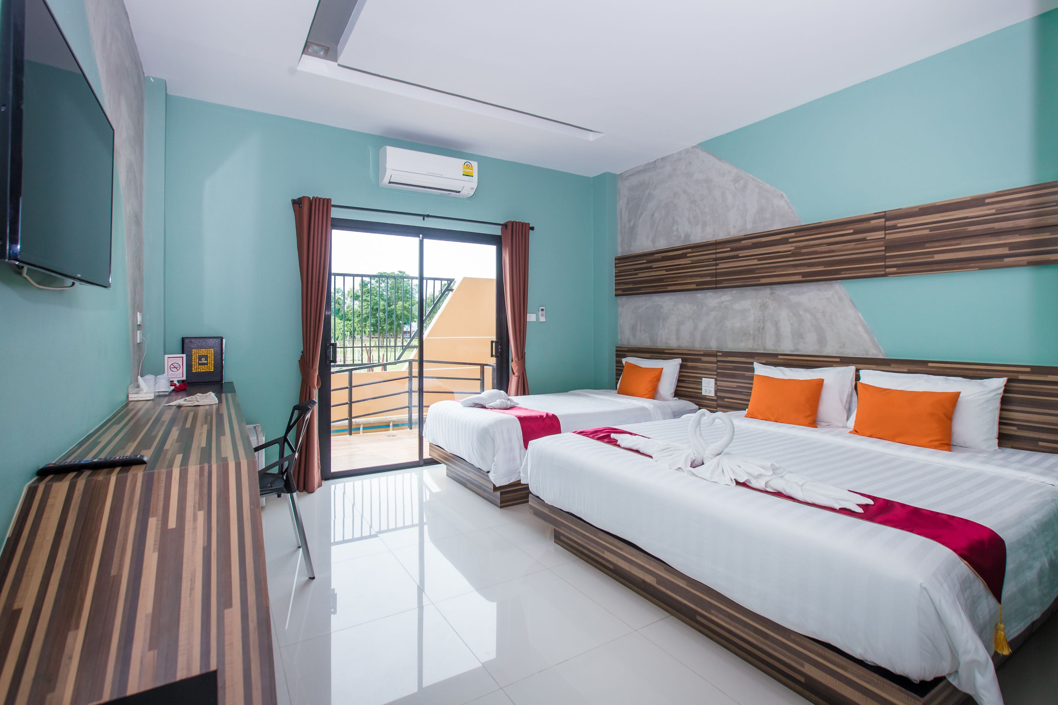 Habitación de hotel con dos camas, televisión, escritorio y balcón.