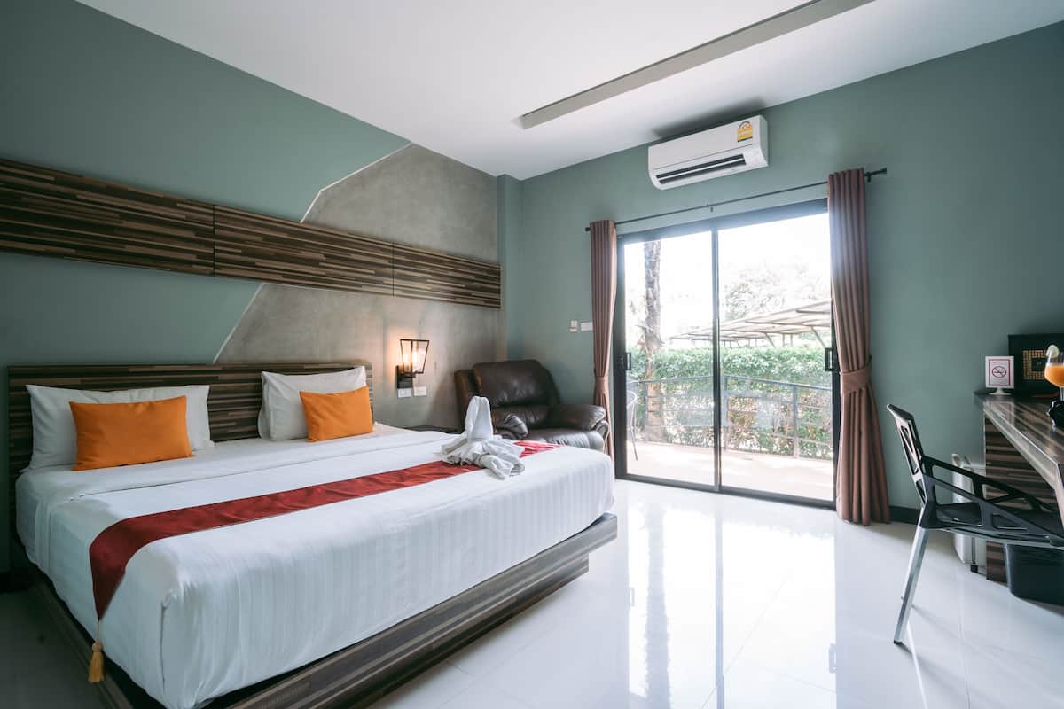 Une chambre d’hôtel moderne, dotée d’un grand lit, d’une chaise, d’un bureau et offrant une vue sur l’extérieur.