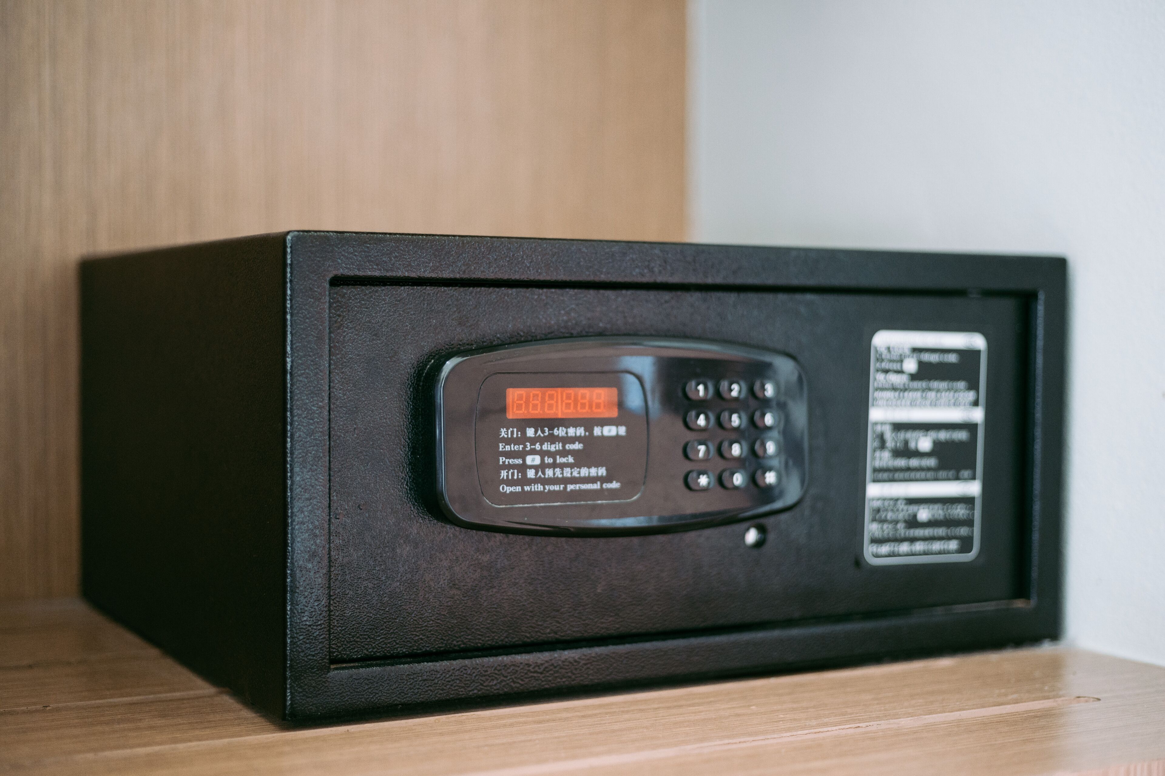 A black safe with a keypad and instructions in multiple languages.