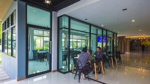 A modern indoor dining area with glass walls, tables, and chairs. - Ray Hotel (Buriram)