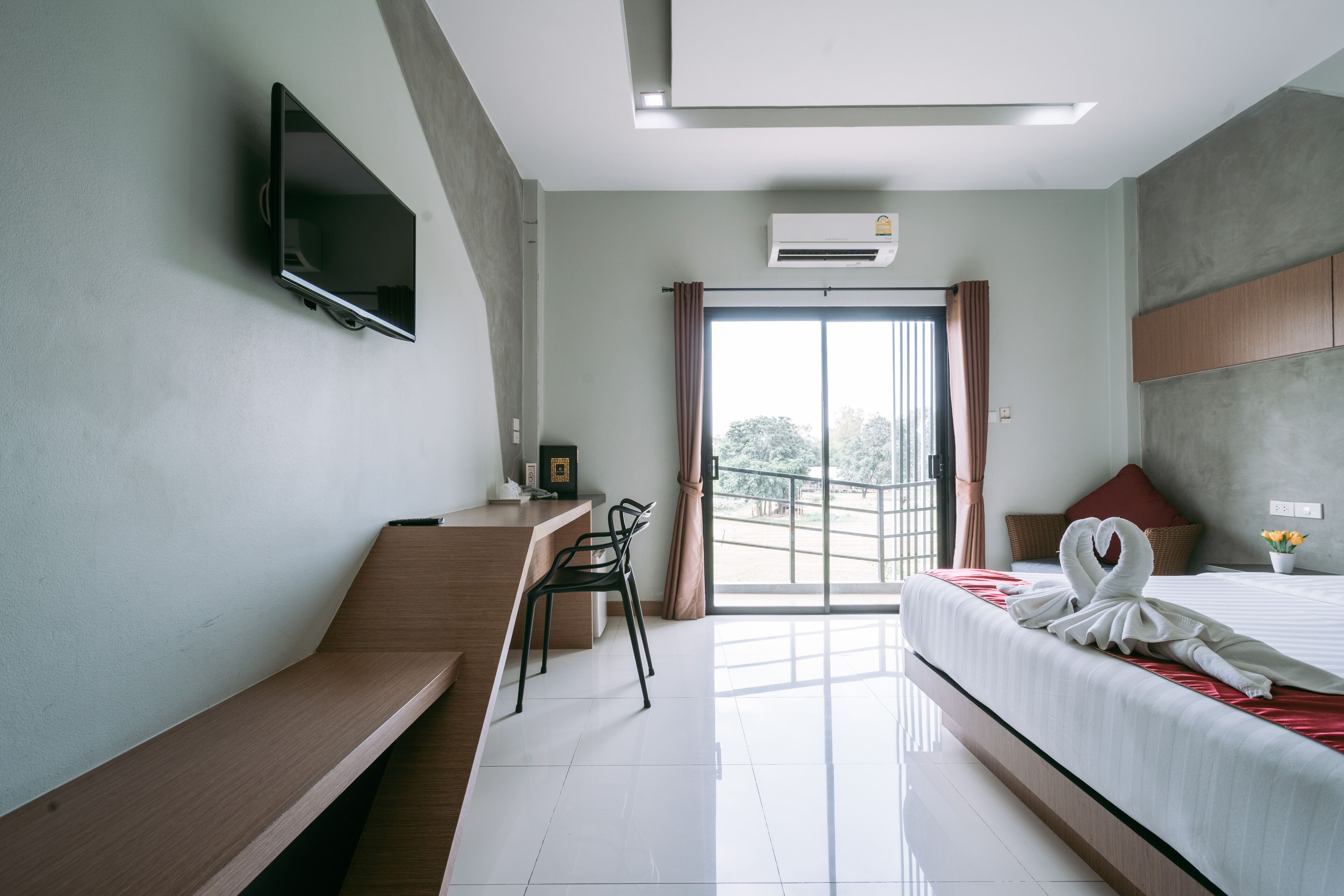 Une chambre d’hôtel équipée d’un lit, d’un bureau, d’une chaise, d’un téléviseur fixé au mur et d’un appareil de climatisation.