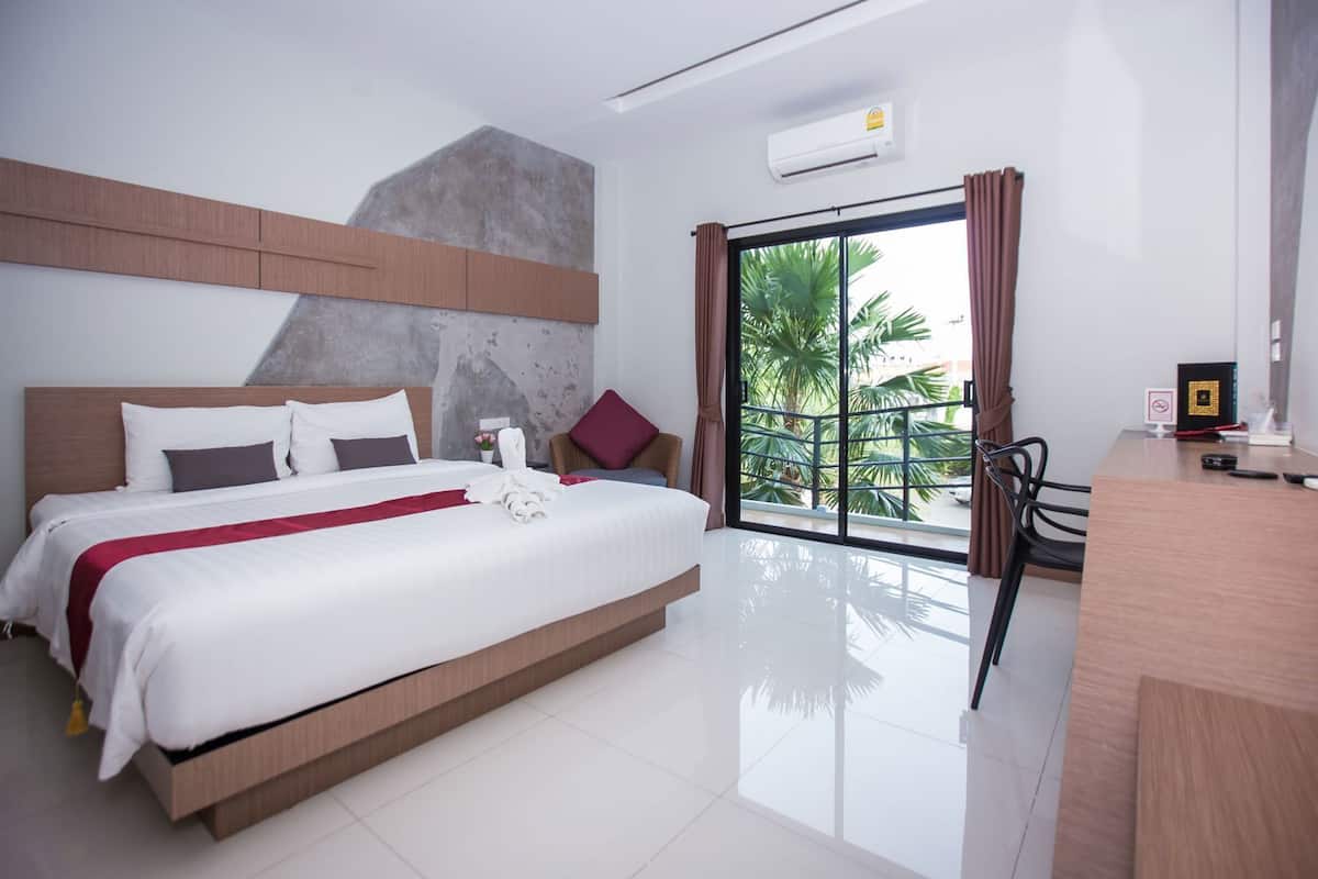 Une chambre d’hôtel moderne avec un grand lit, un bureau et une vue sur les palmiers.