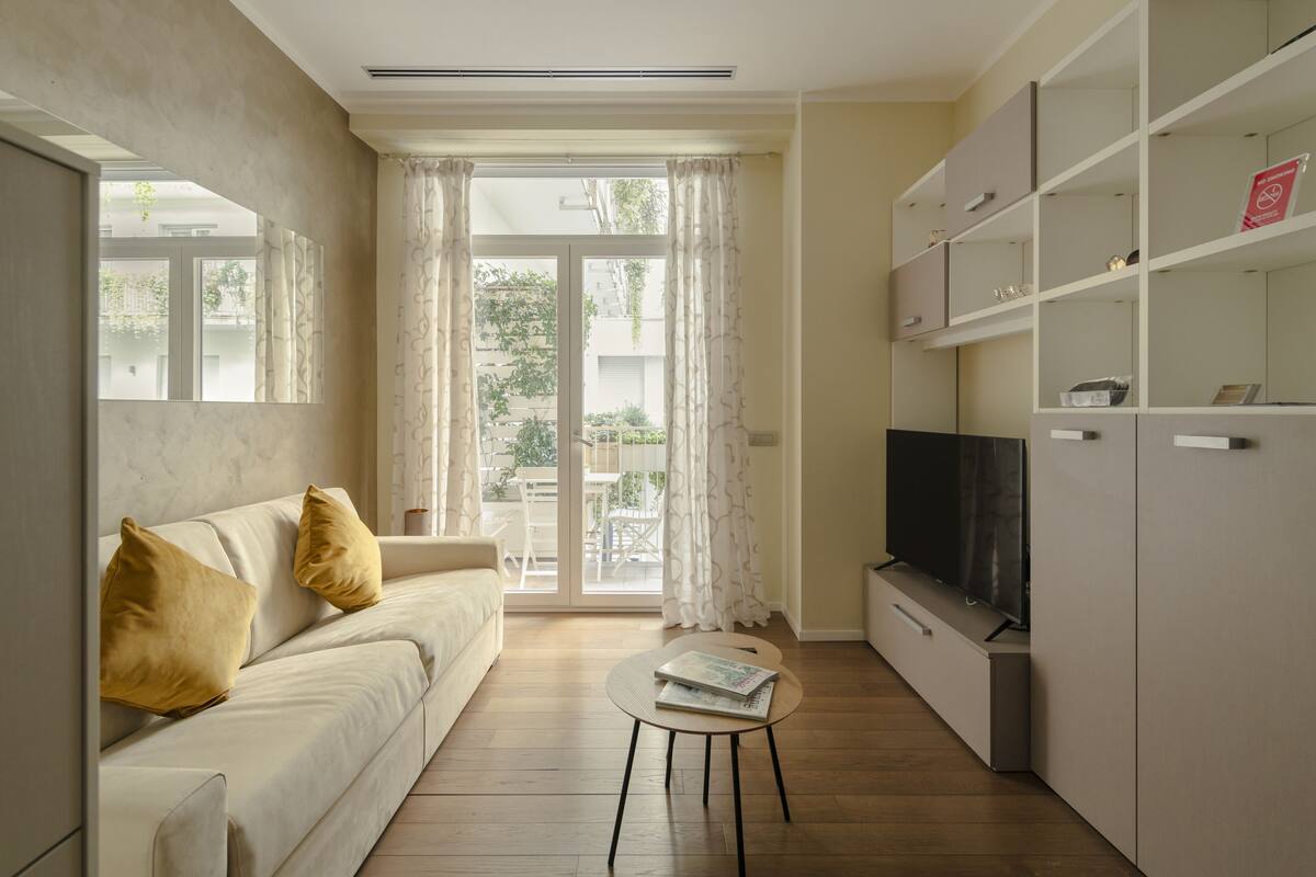 Una sala de estar con un sofá, una mesa de centro, un televisor y una estantería.