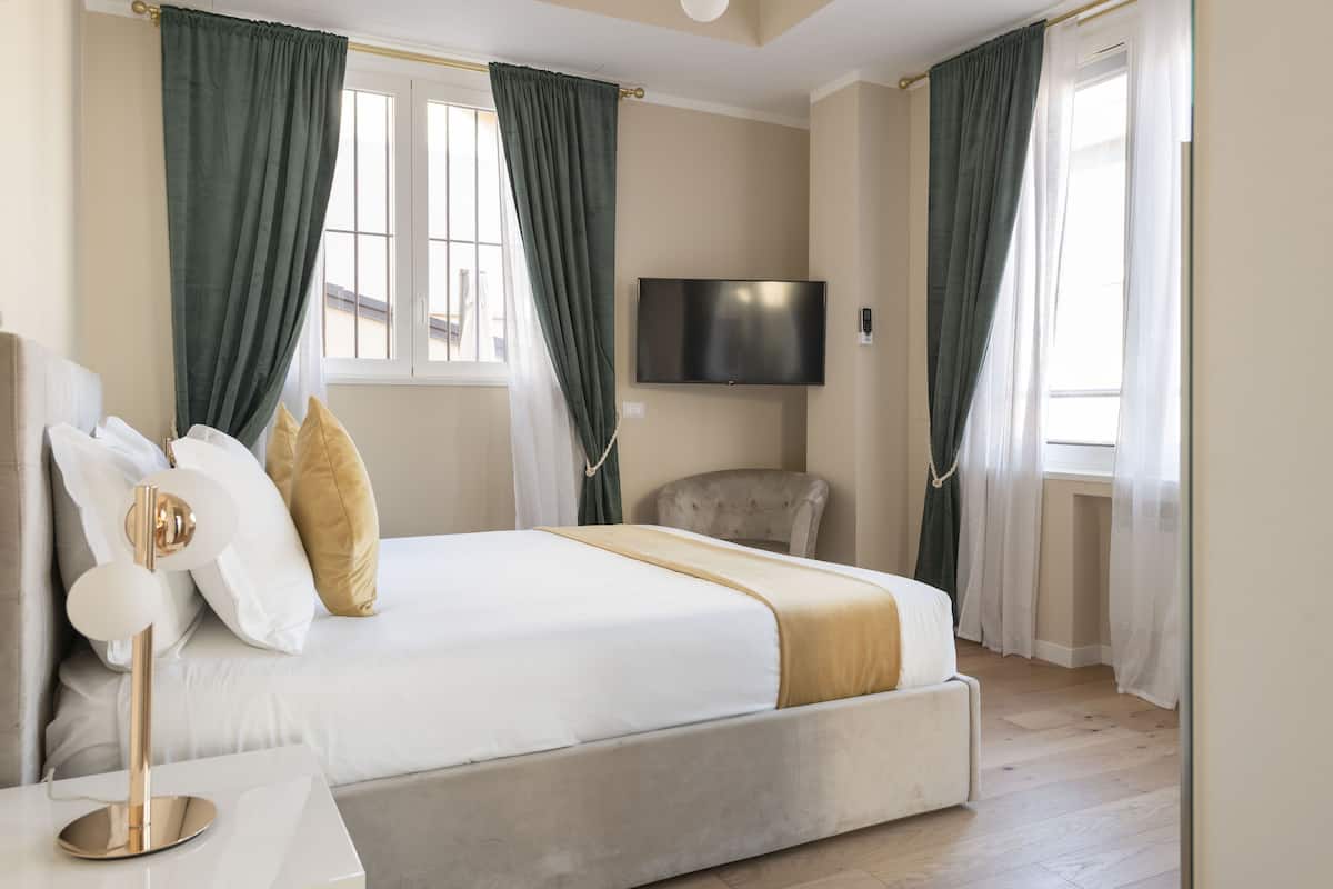 Una habitación de hotel moderna con una cama grande, un televisor de pantalla plana y una silla.