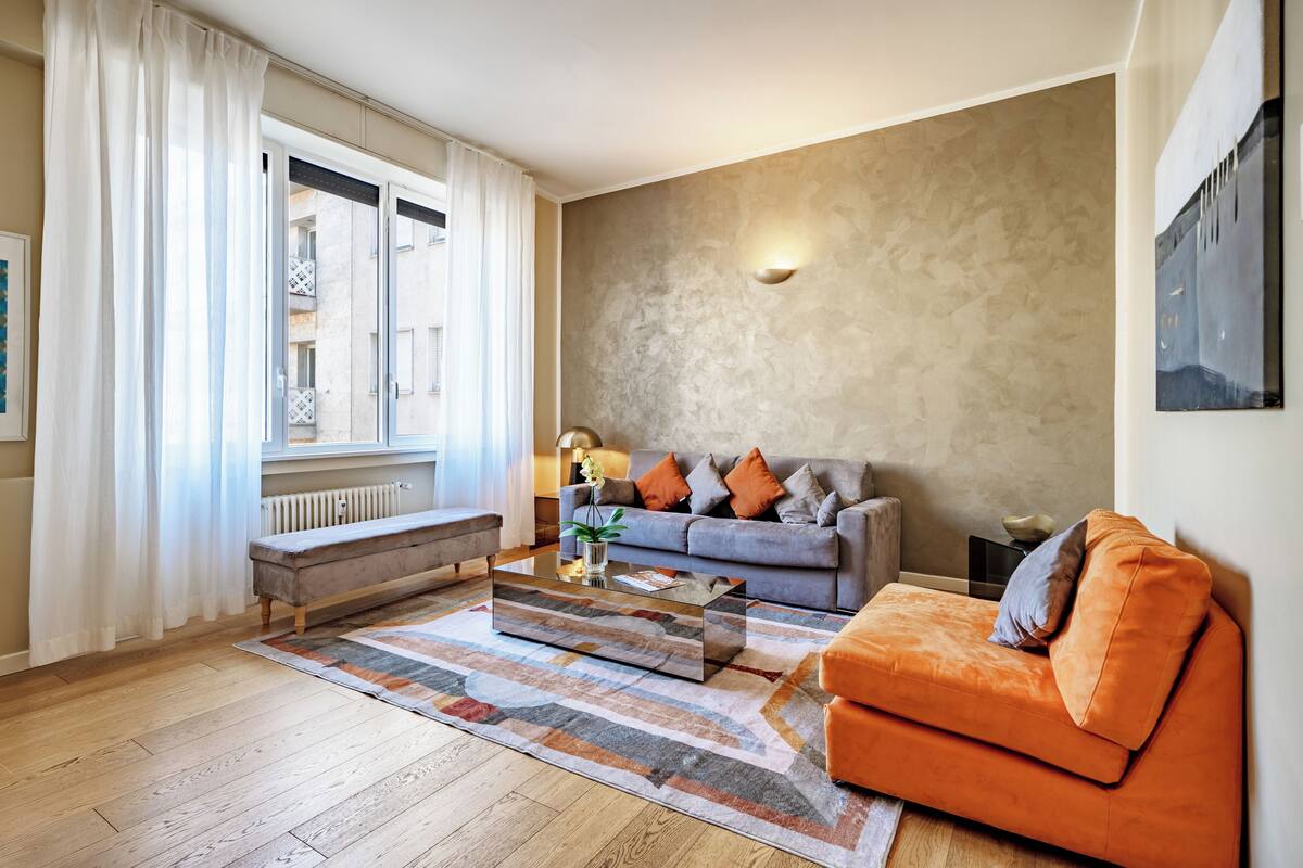 Una sala de estar moderna con un sofá gris, un sofá naranja y una mesa de centro.