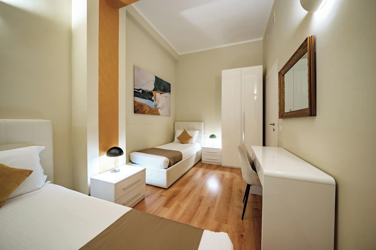 Un dormitorio moderno con cama, mesita de noche, lámpara y un escritorio con silla.