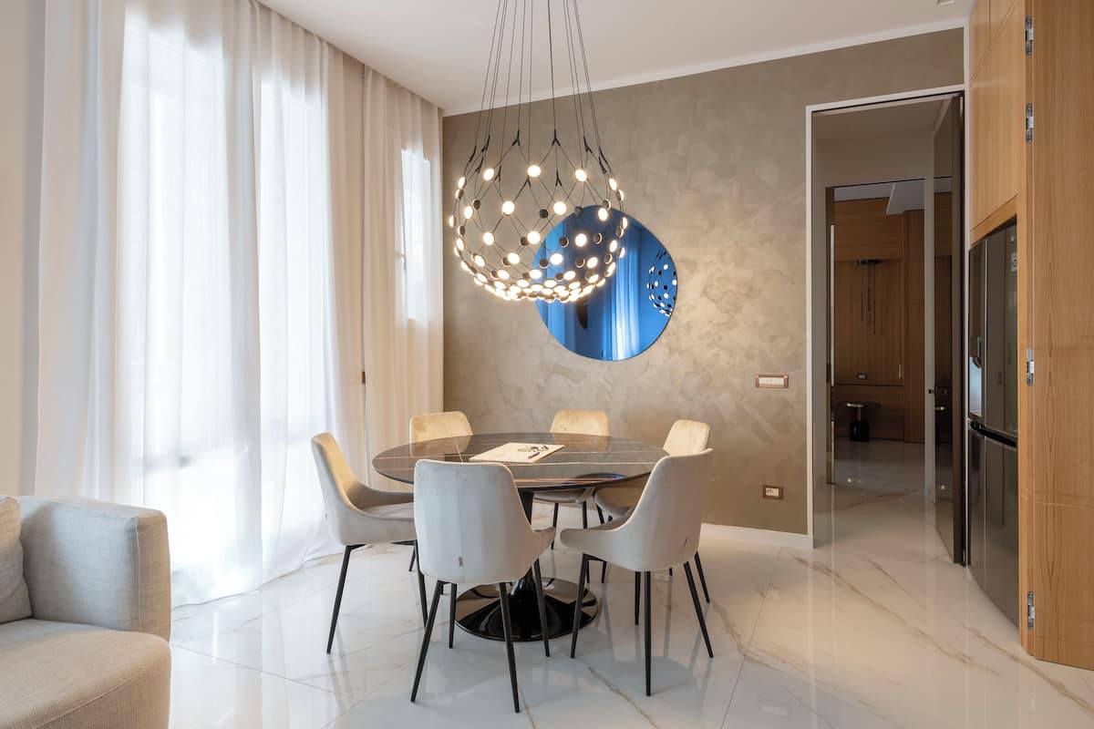 Un comedor moderno con una mesa redonda, seis sillas y una lámpara colgante original.