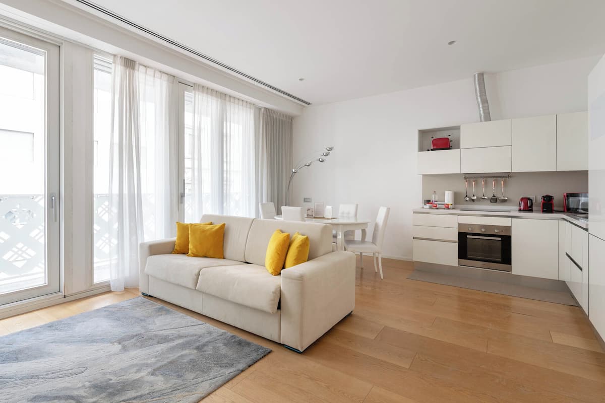 Una sala de estar moderna con un sofá, una mesa de comedor y una cocina con armarios y electrodomésticos.