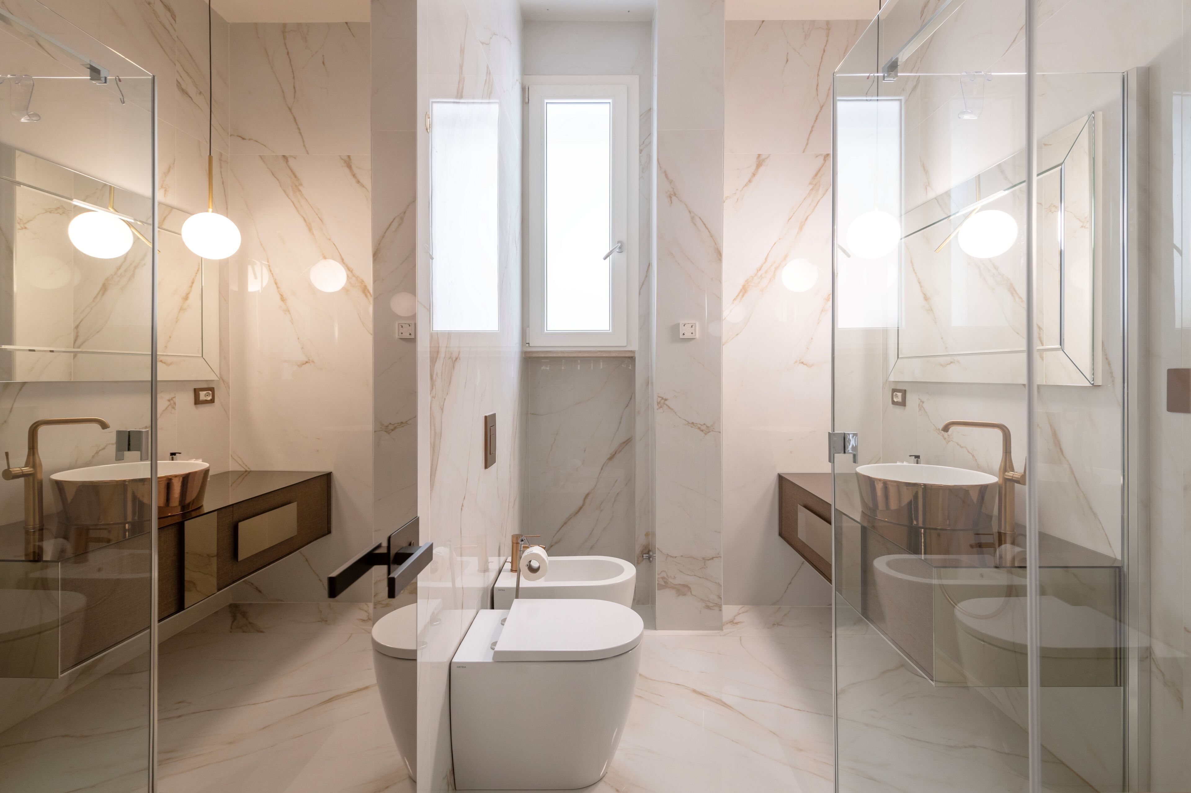 Une salle de bain moderne avec une douche à parois de verre, deux lavabos et des toilettes.