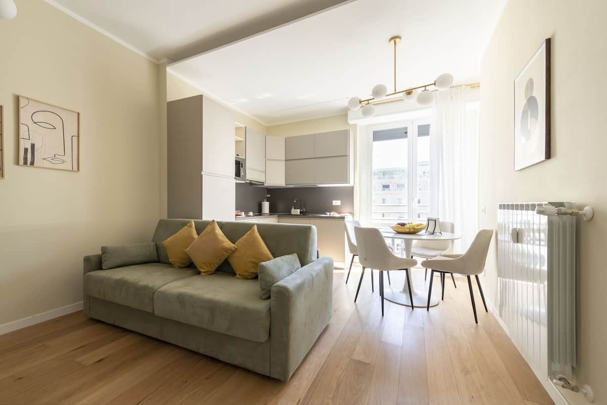 Una sala de estar moderna con un sofá gris, sillas blancas y una mesa de comedor.