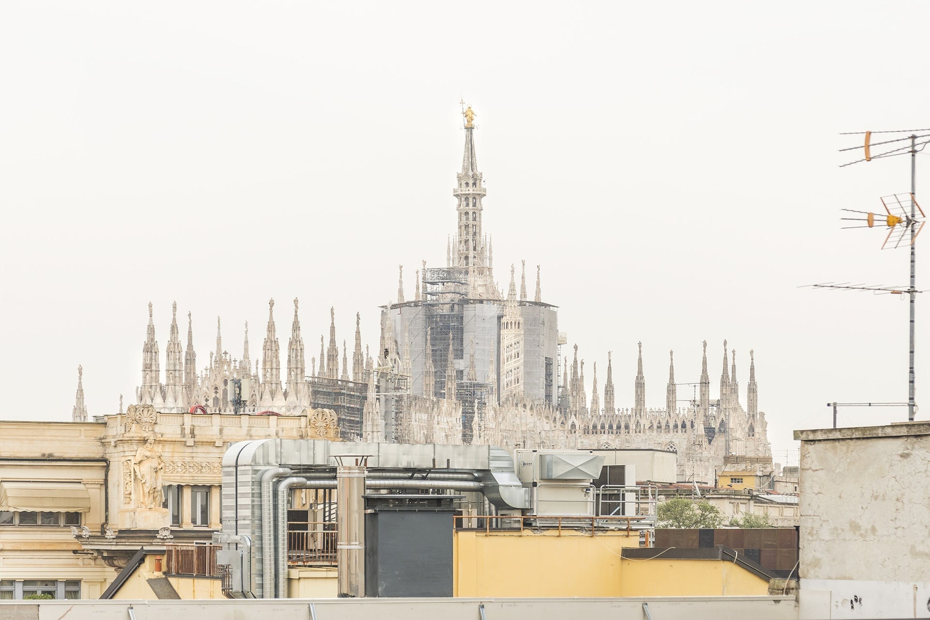 A historic cathedral with intricate spires and a clock tower, surrounded by modern buildings.