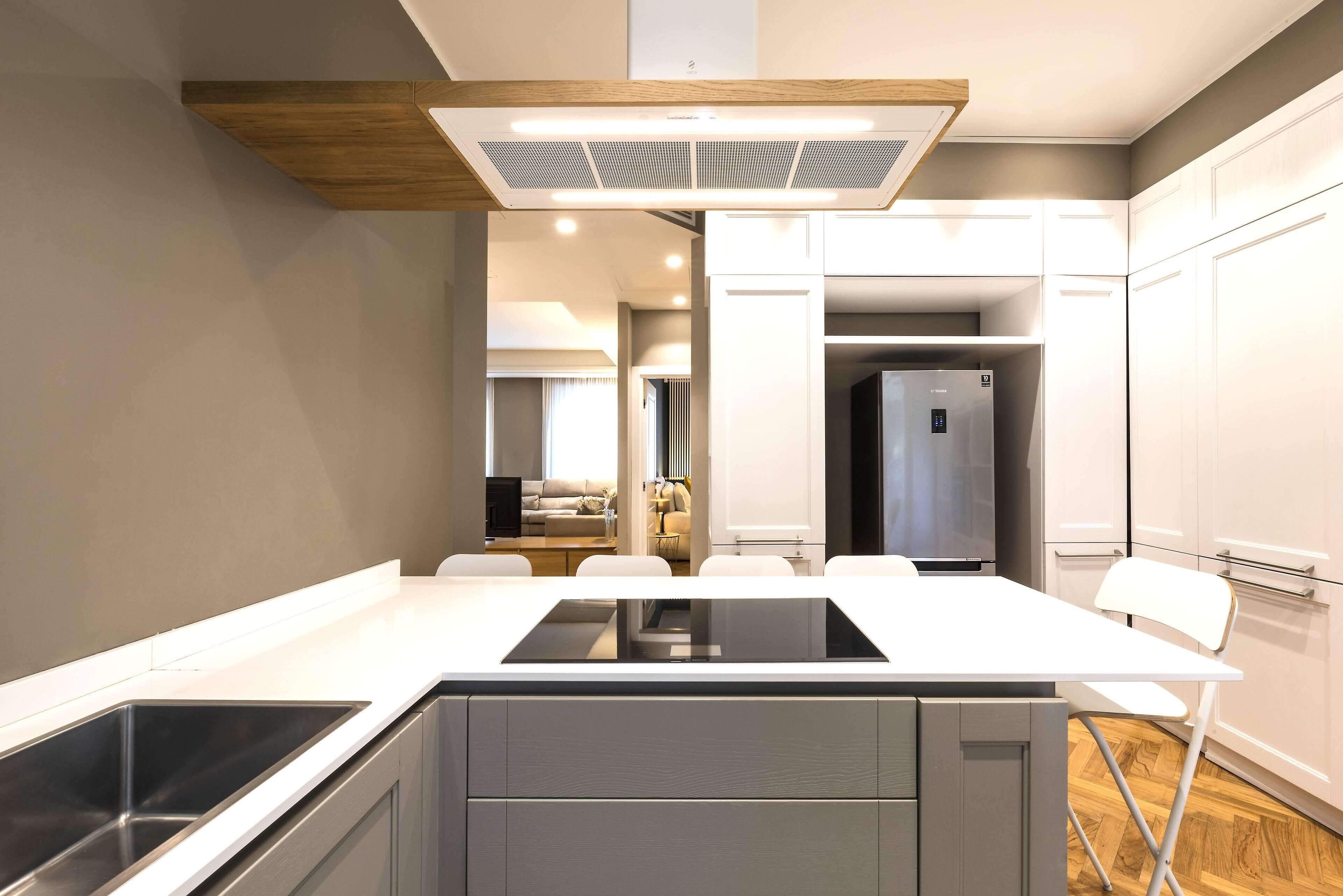 Een moderne keuken met een centraal eiland, witte kasten en een ingebouwde kookplaat.