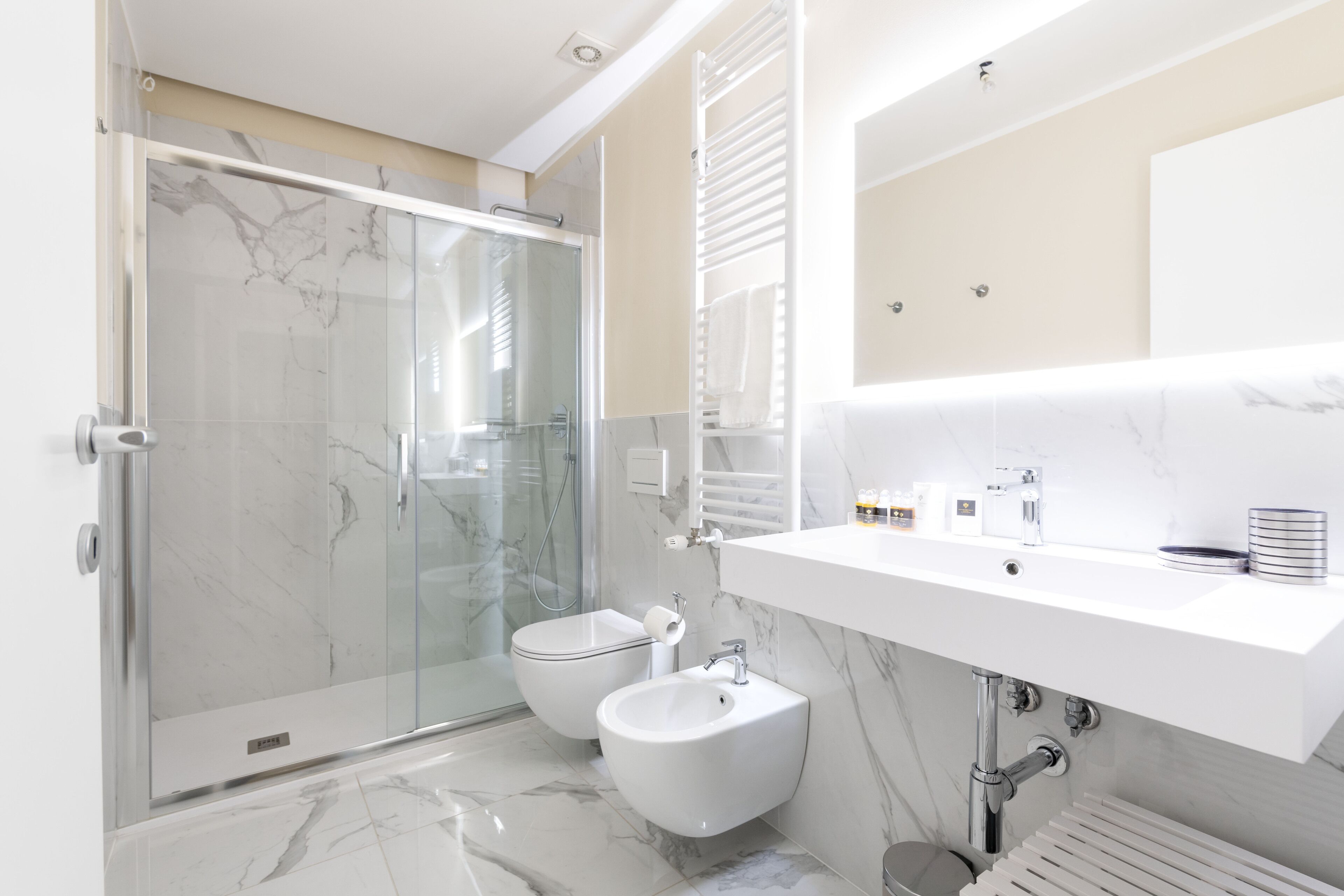 A modern bathroom with a glass shower enclosure, a white sink, and a bidet.