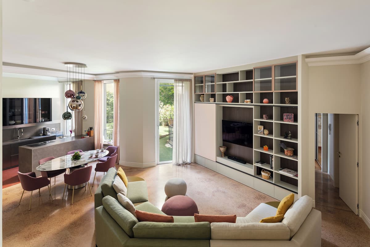 Una sala de estar moderna con un sofá verde, una mesa de comedor y una zona de cocina.