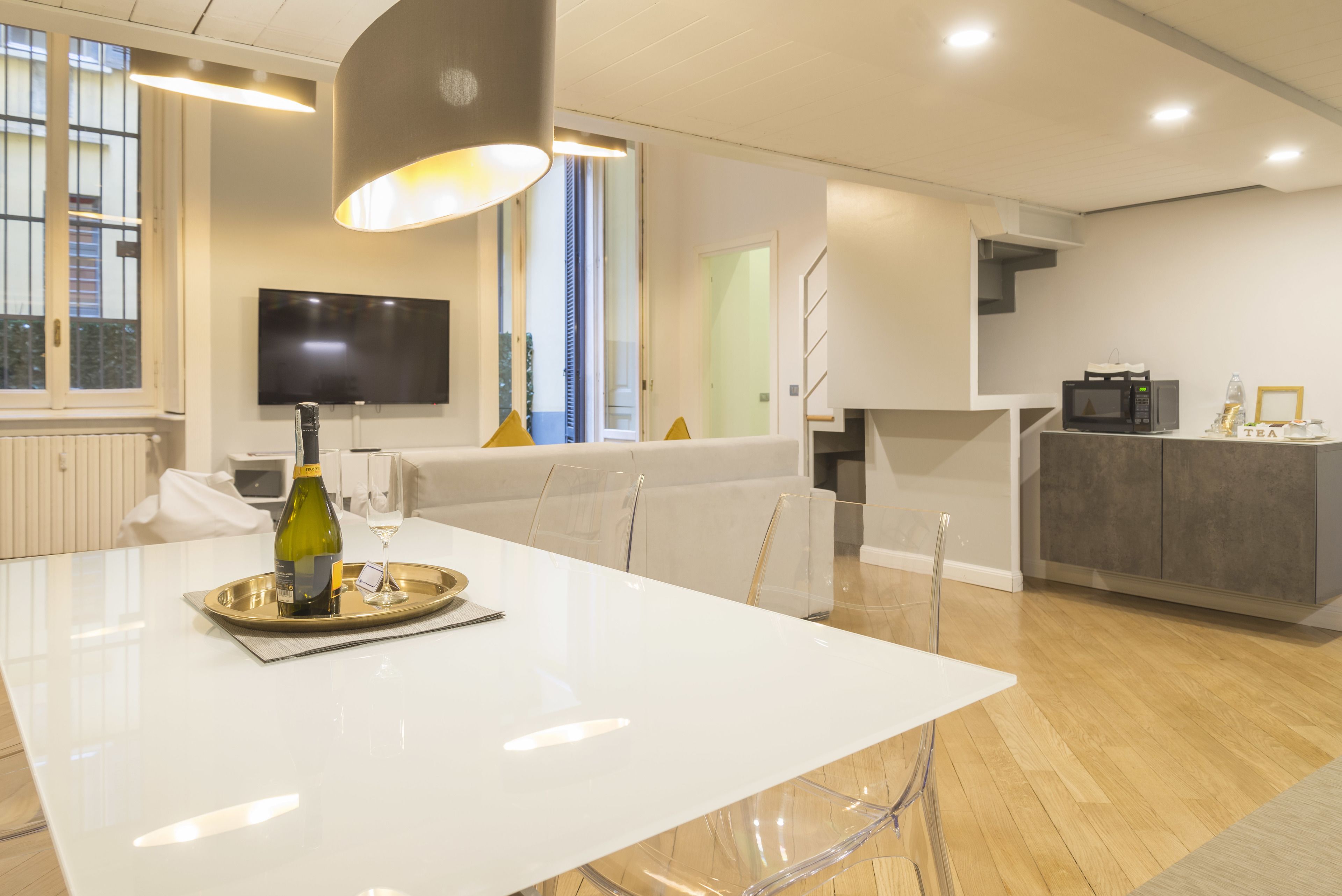 A modern kitchen with a dining area, a flat-screen TV, and a microwave.